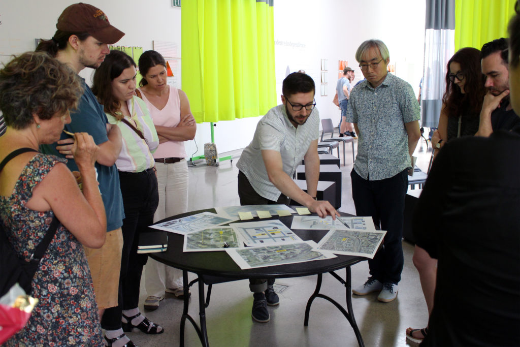 People stand around a table referencing source materials on the topic of the Built Environment