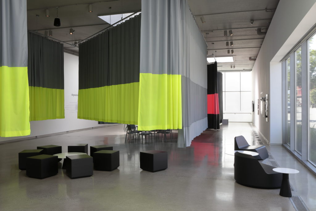 Color-blocked curtains hang from the ceiling and black modular seating appear in the ICA's Beverly Reynolds Gallery